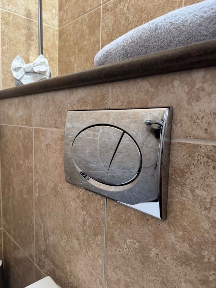 Chrome flush plate polished to a shine against beige tiles