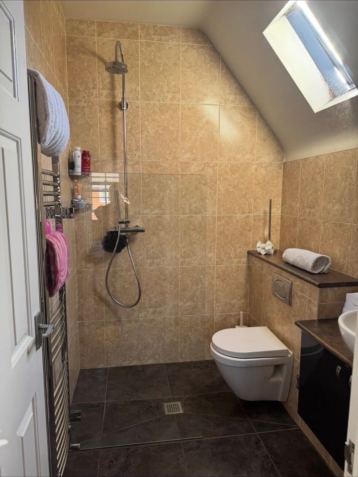 Walk-in shower room with clean tiles, glass and wall-hung toilet