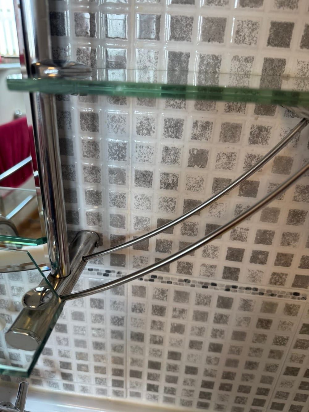 After cleaning: chrome and glass corner shower shelf against mosaic tiles