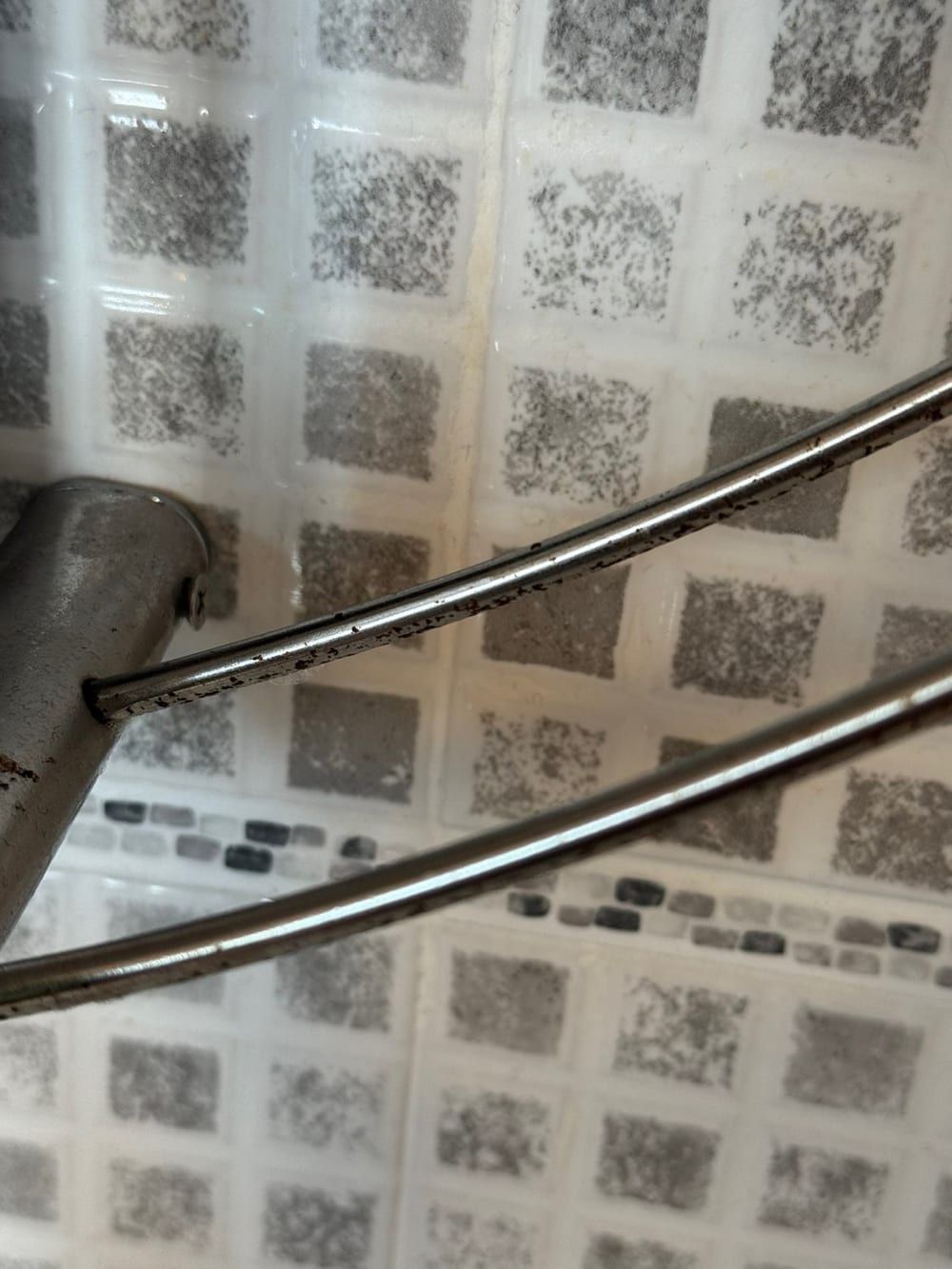 Before cleaning: chrome and glass corner shower shelf against mosaic tiles